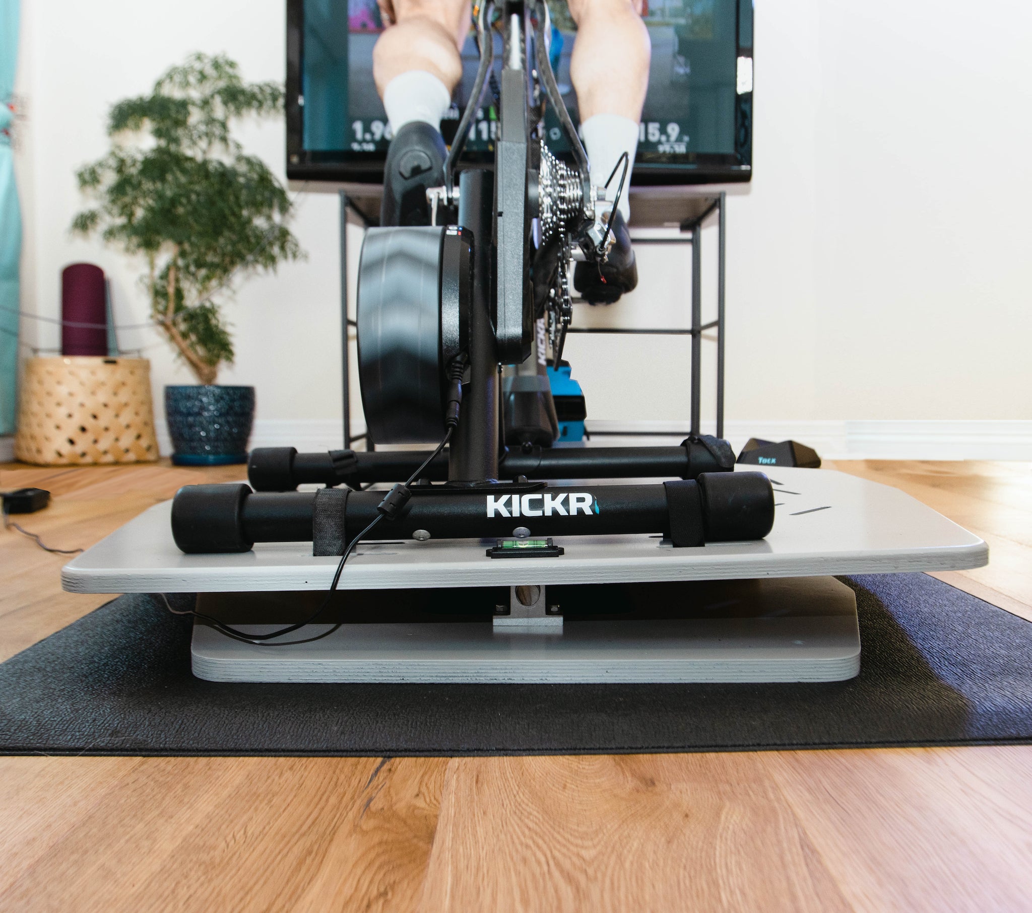 Rear view of a rider using the Kickr Core and Kickr Climb on top of the Velocity Rocker rocker plate while using Wahoo Systm for indoor training.