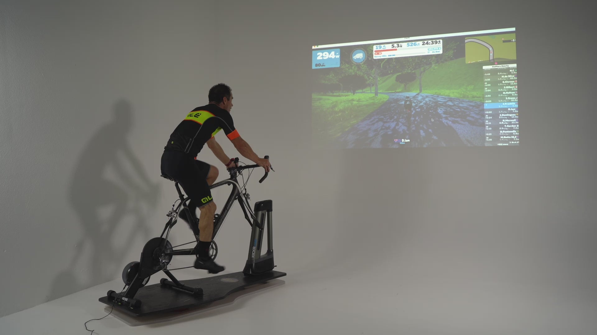 Man riding Specialized bike and Wahoo Kickr Core and Kickr Climb on top of the Velocity Rocker rocker plate using Zwift in white space.